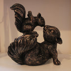 Bronze resin sculpture of a squirrel and pup on a white surface with a neutral background
