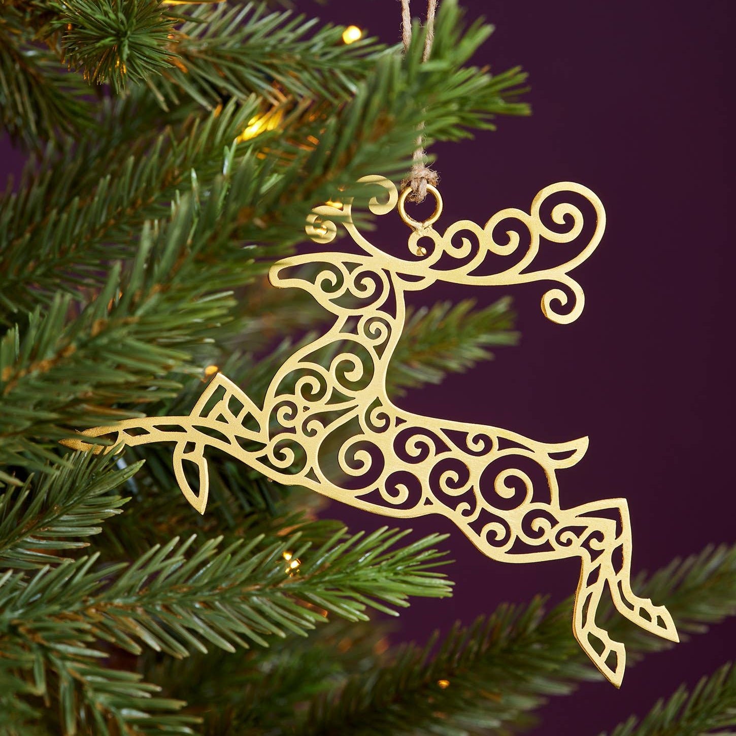 Decorative gold reindeer ornament on a Christmas tree with a dark purple background